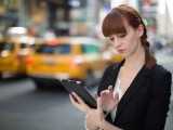 Foto che mostra una donna che usa un iPad in strada