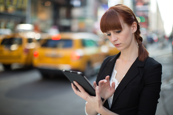 Foto che mostra una donna che usa un iPad in strada